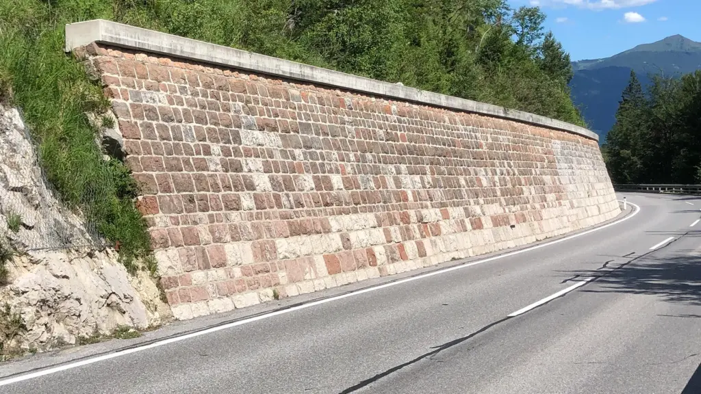 Steinmauer an einer Straße in bergiger Landschaft