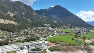 Panorama einer Alpenlandschaft mit Dorf und Bergen.