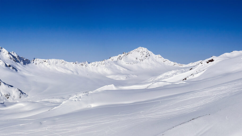 Verschneite Berglandschaft unter blauem Himmel.