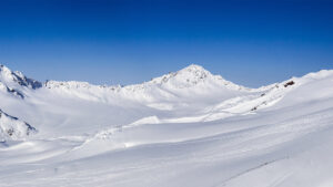 Verschneite Berglandschaft unter blauem Himmel.