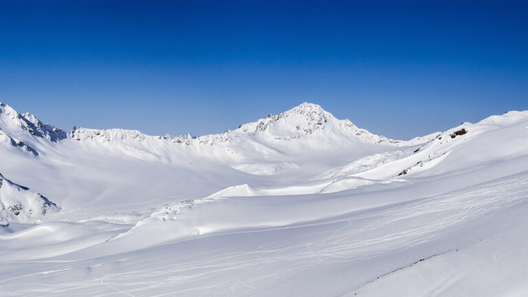 Verschneite Berglandschaft unter blauem Himmel.